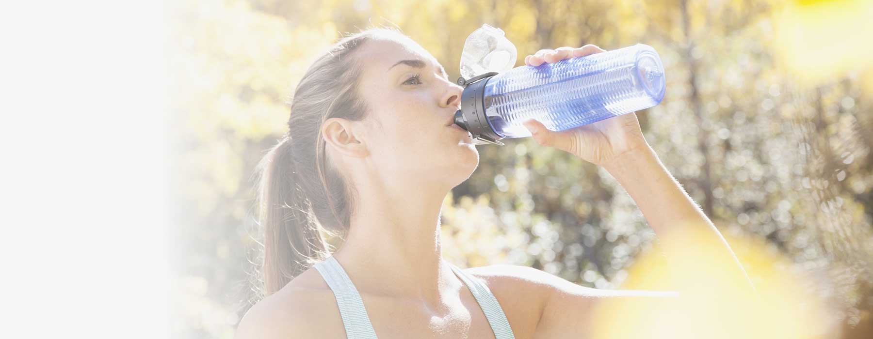 Woman drinking Skybright Performance Electrolytes from water bottle.