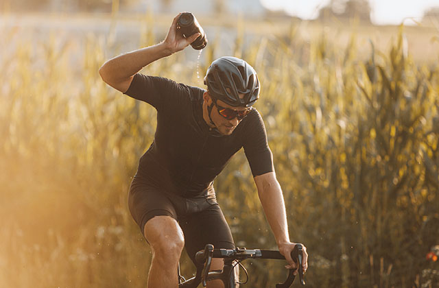 Man cycling and cooling himself from water bottle