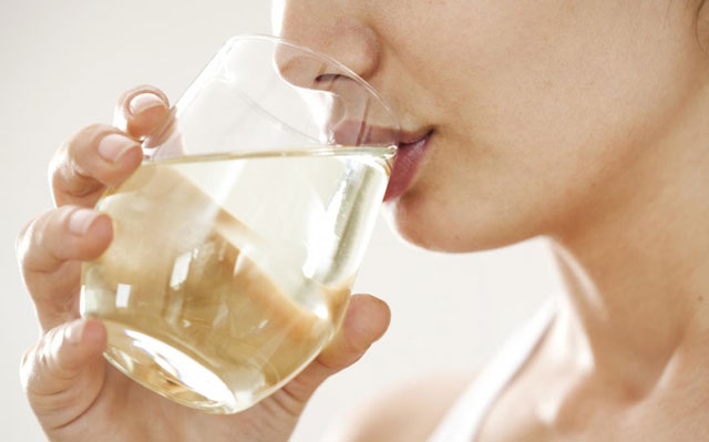 Close-up of woman drinking Organic Apple Cider Vinegar with water from a glass.