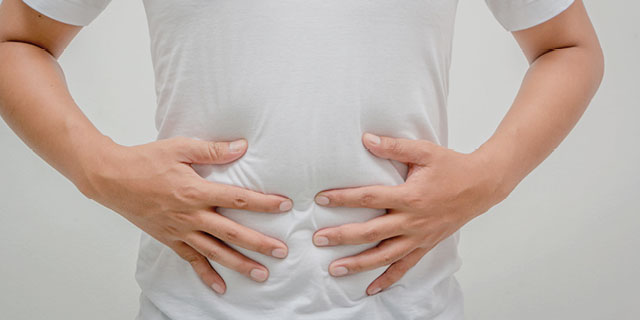 Man holding stomach. Friendly gut bacteria and probiotics such as lactoferrin play a vital role in iron absorption.