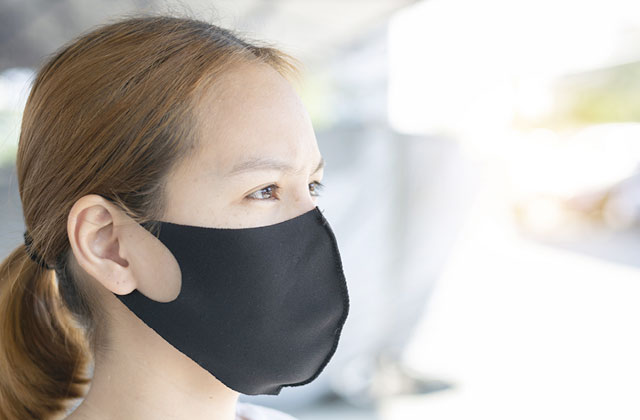 Young woman wearing black fabric mask. Spray it with Colloidal Silver, as well as spraying a little on your face to avoid bacterial build-up.