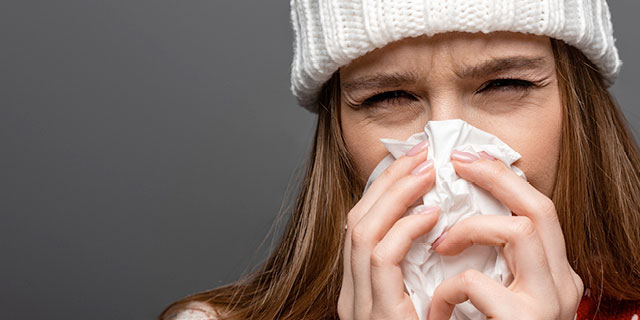 Woman blowing nose in tissue. When feeling unwell, take 5ml of colloidal silver liquid three times a day for five days.