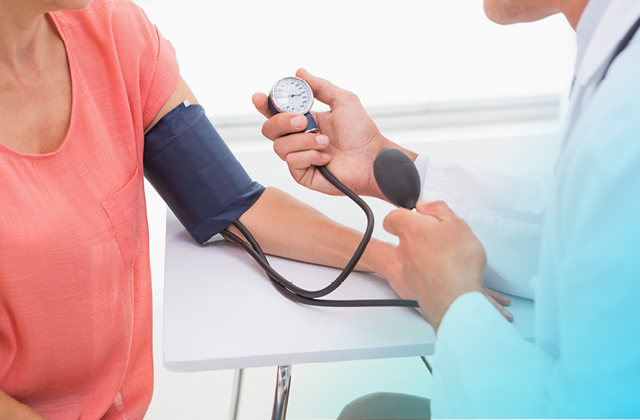 Doctor taking woman's blood pressure reading.