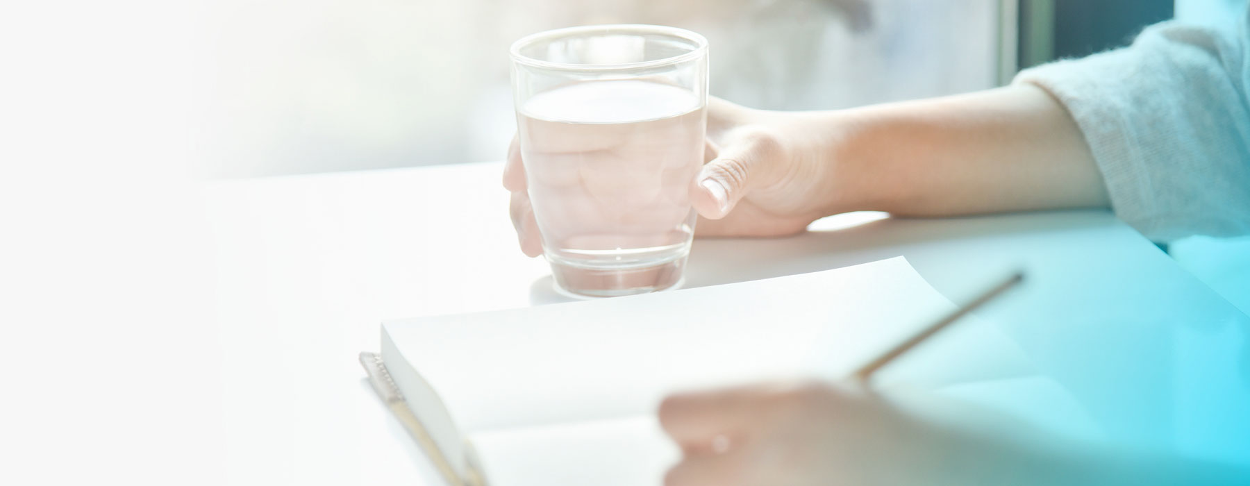 woman writing noted in book while drinking mineral supplements